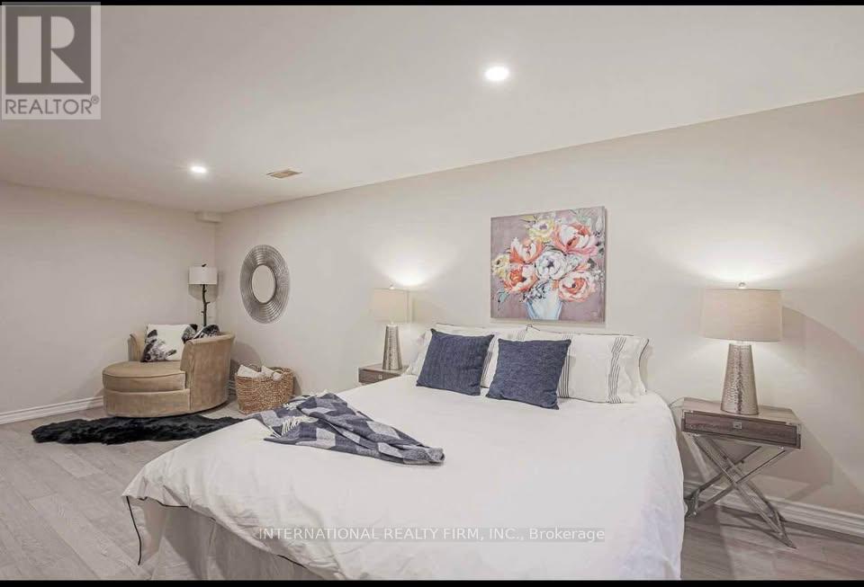 A bedroom with a large bed, a round mirror, and a painting on the wall.