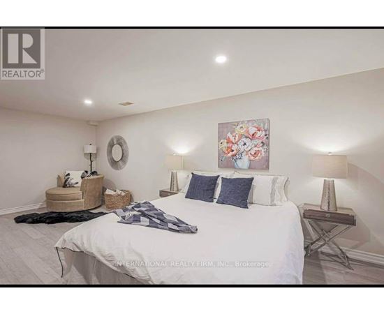 A bedroom with a large bed, a round mirror, and a painting on the wall.
