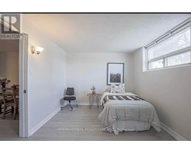 A bedroom with a bed, chair, and a painting on the wall.