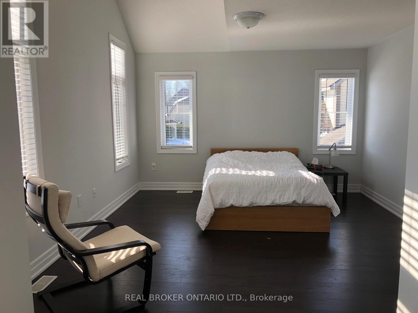 A bedroom with a bed, chair, and window.