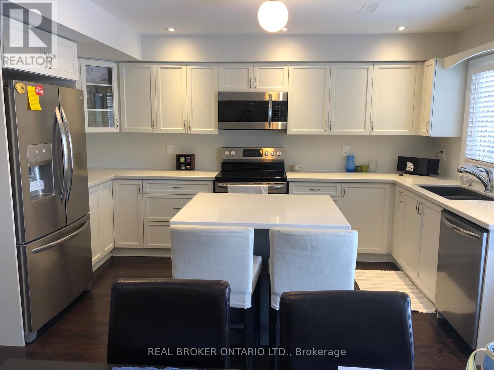 A kitchen with white cabinets and a refrigerator.