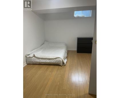 A bedroom with a white bed and wooden flooring.