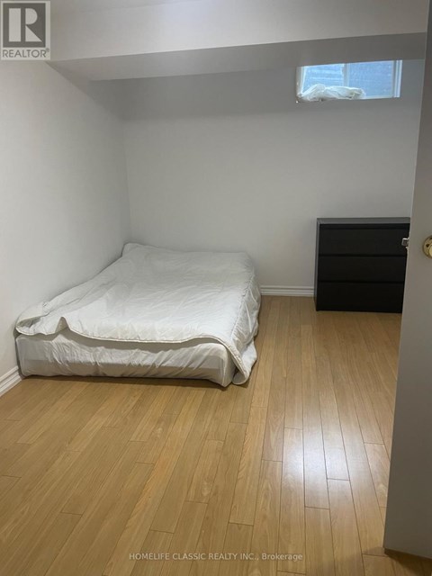 A bedroom with a white bed and wooden flooring.