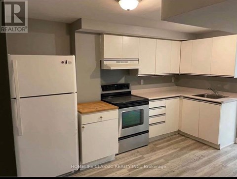 A white refrigerator is in a kitchen with white cabinets.