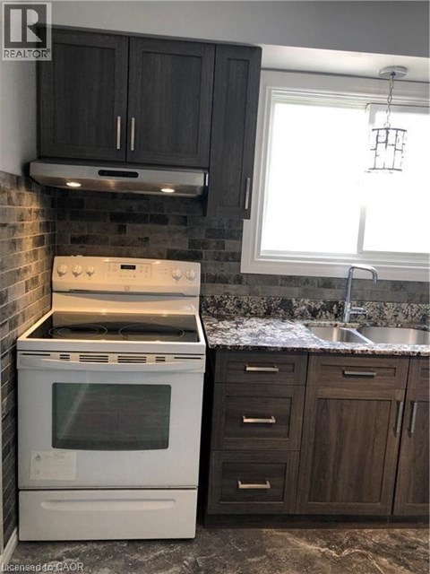 A white oven and stove top are in a kitchen with dark wood cabinets.