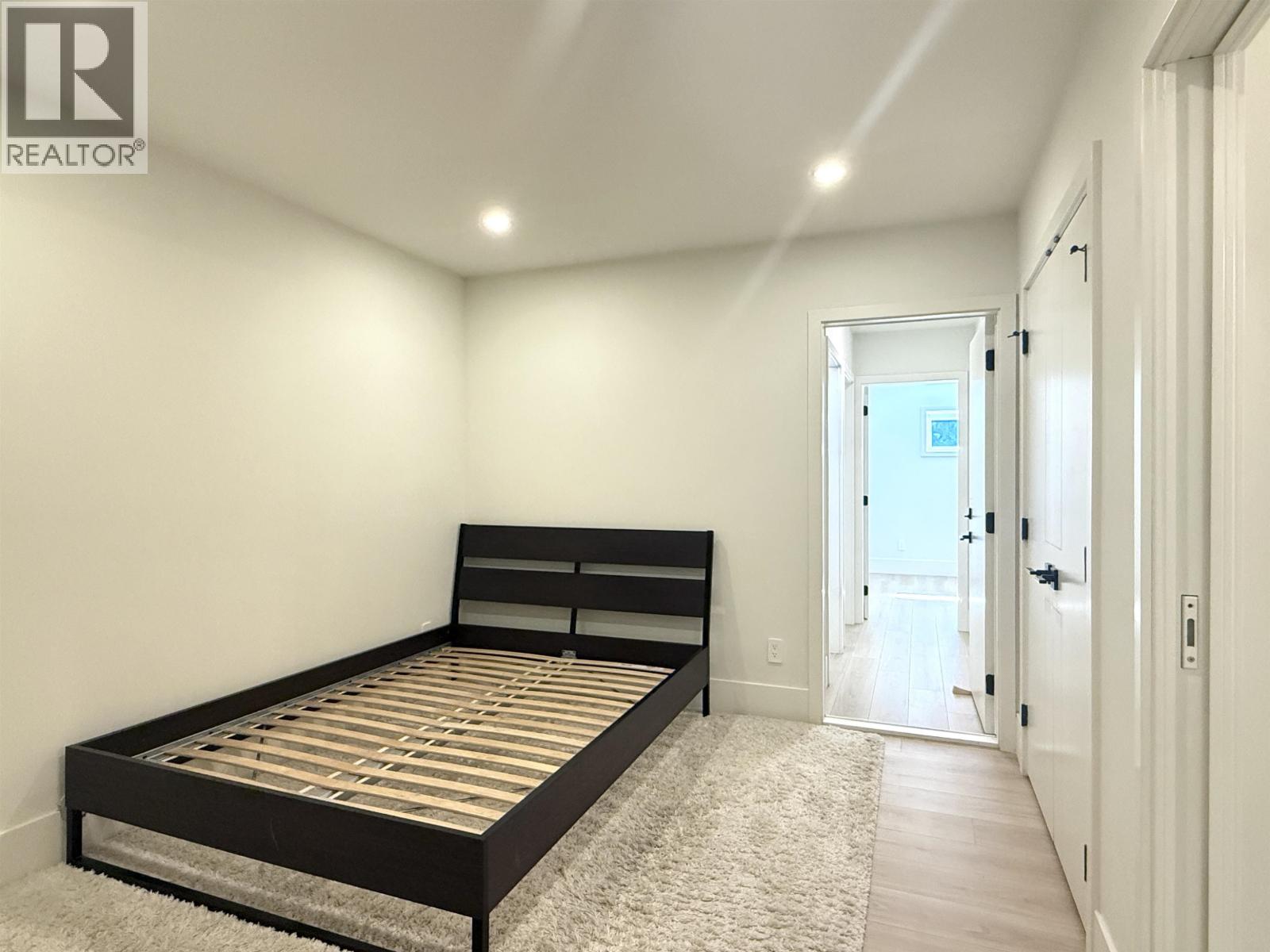 A bedroom with a bed, carpet, and a door leading to a balcony.