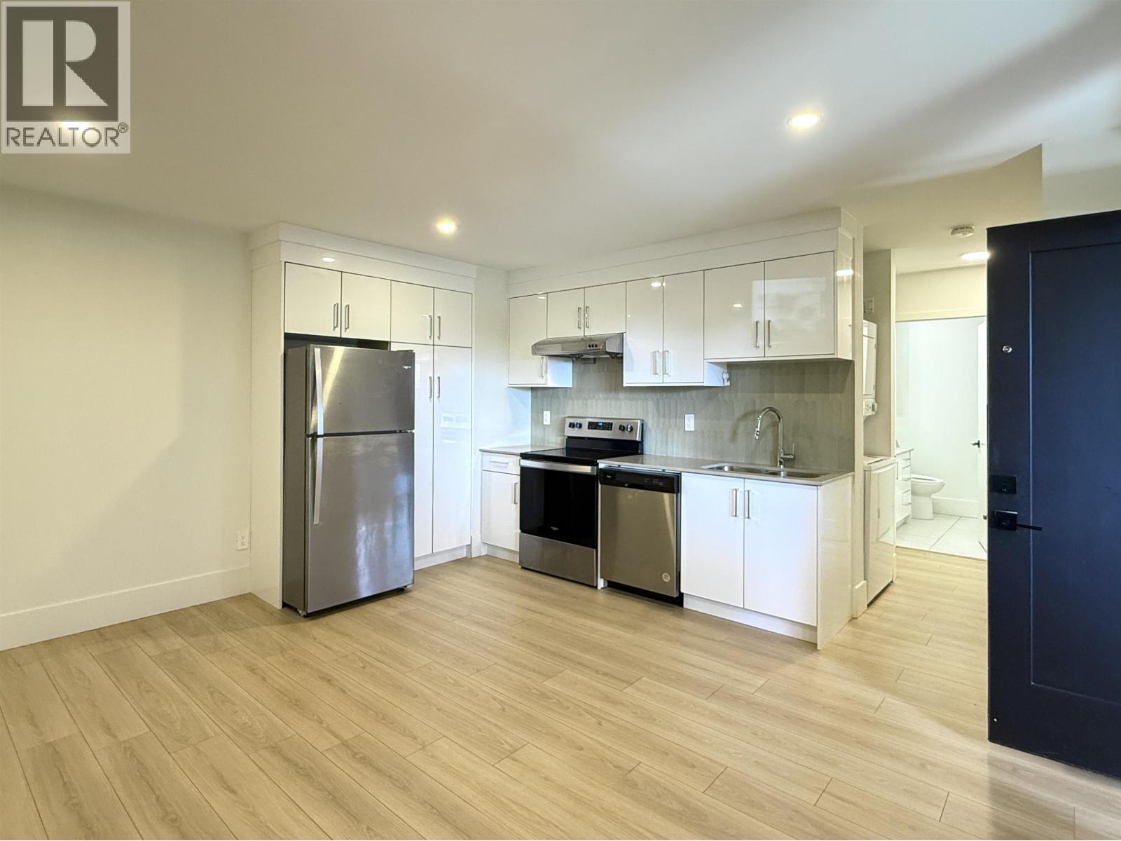 A kitchen with a refrigerator, stove, and sink.