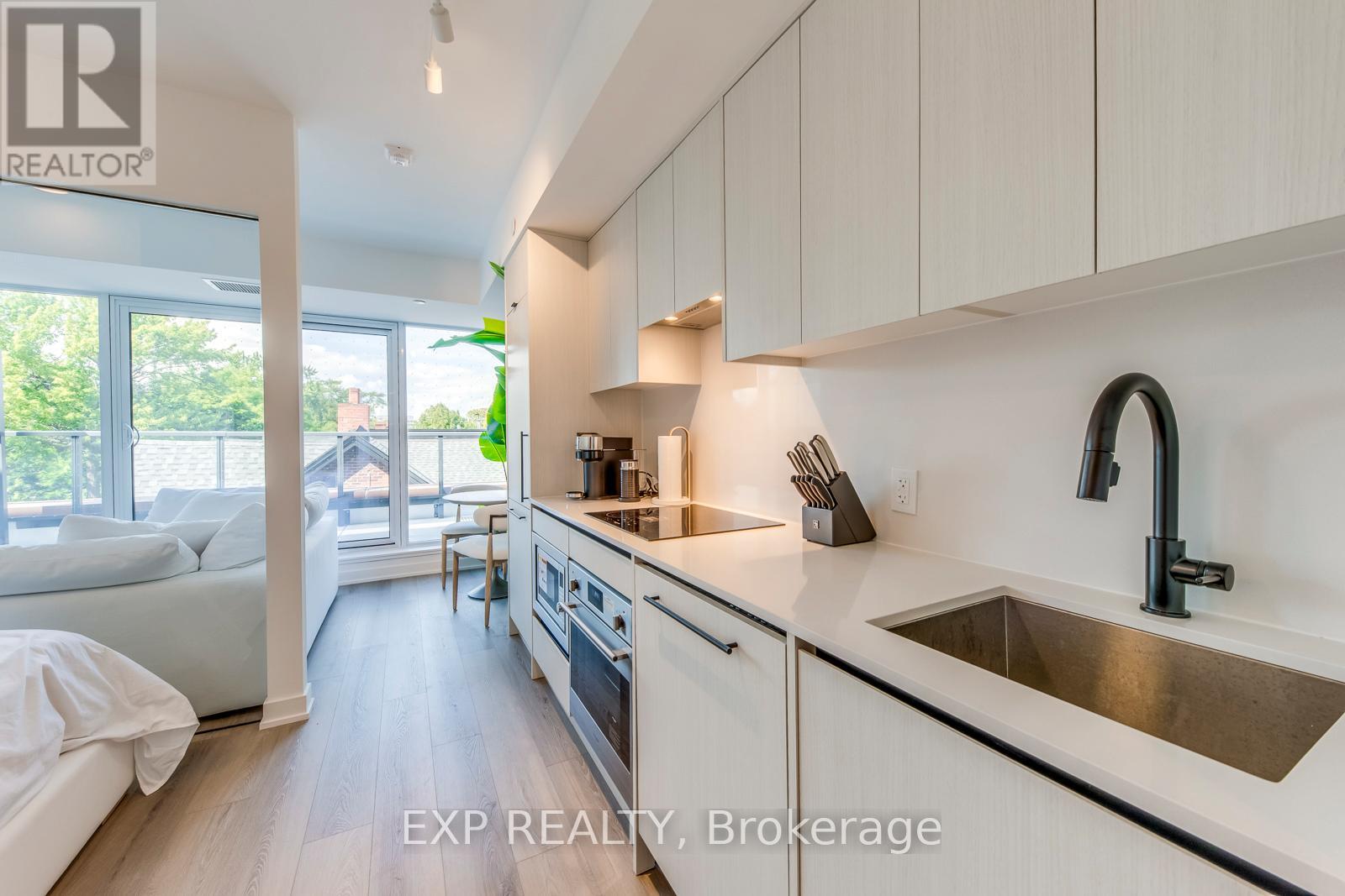 A modern kitchen with white cabinets and a stainless steel sink.