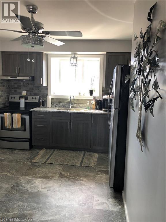 A modern kitchen with a black refrigerator and a ceiling fan.