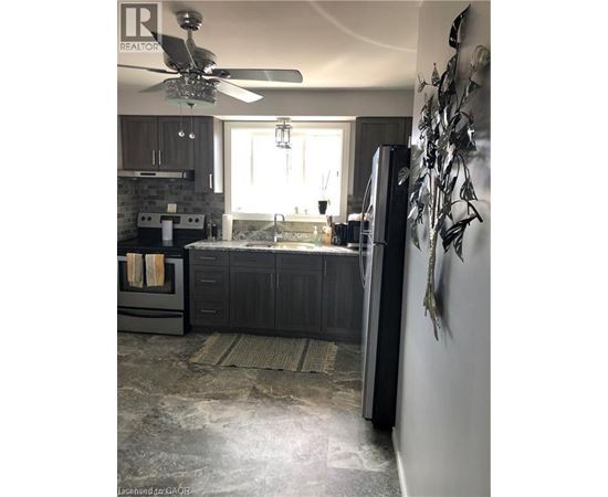A modern kitchen with a black refrigerator and a ceiling fan.
