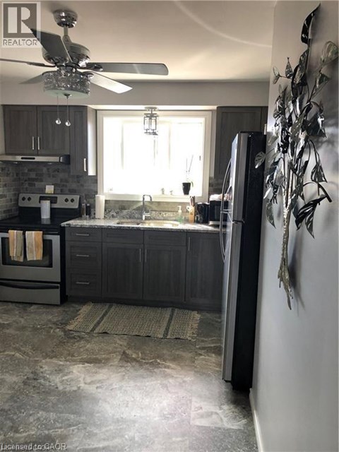 A modern kitchen with a black refrigerator and a ceiling fan.