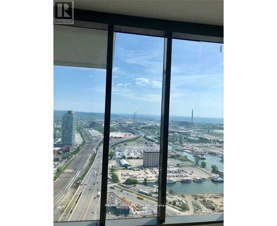 A view from a high-rise window looking out at a busy highway and a body of water.