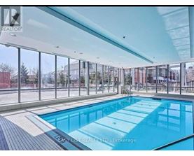 A large indoor swimming pool with a glass wall surrounding it.
