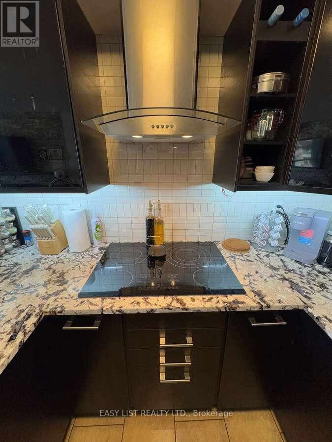 A modern kitchen with a black countertop and a stove top.