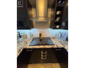 A modern kitchen with a black countertop and a stove top.