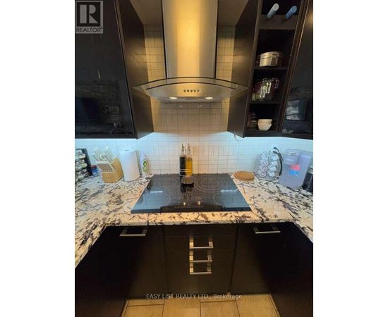 A modern kitchen with a black countertop and a stove top.