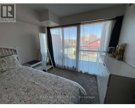 A bedroom with a large bed and a window with curtains.