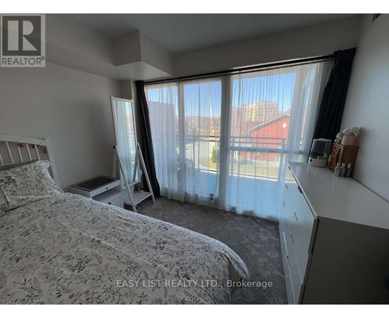 A bedroom with a large bed and a window with curtains.