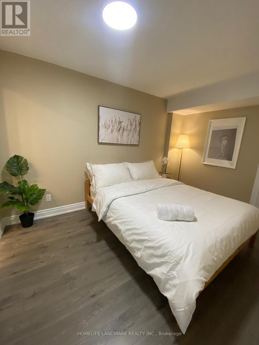 A bedroom with a bed, a potted plant, and two framed pictures on the wall.