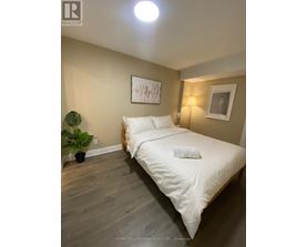 A bedroom with a bed, a potted plant, and two framed pictures on the wall.