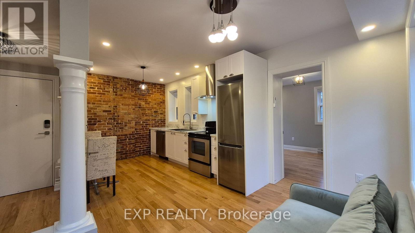 A kitchen with a brick wall and wooden floors.