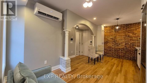 A living room with a grey couch and a brick wall.