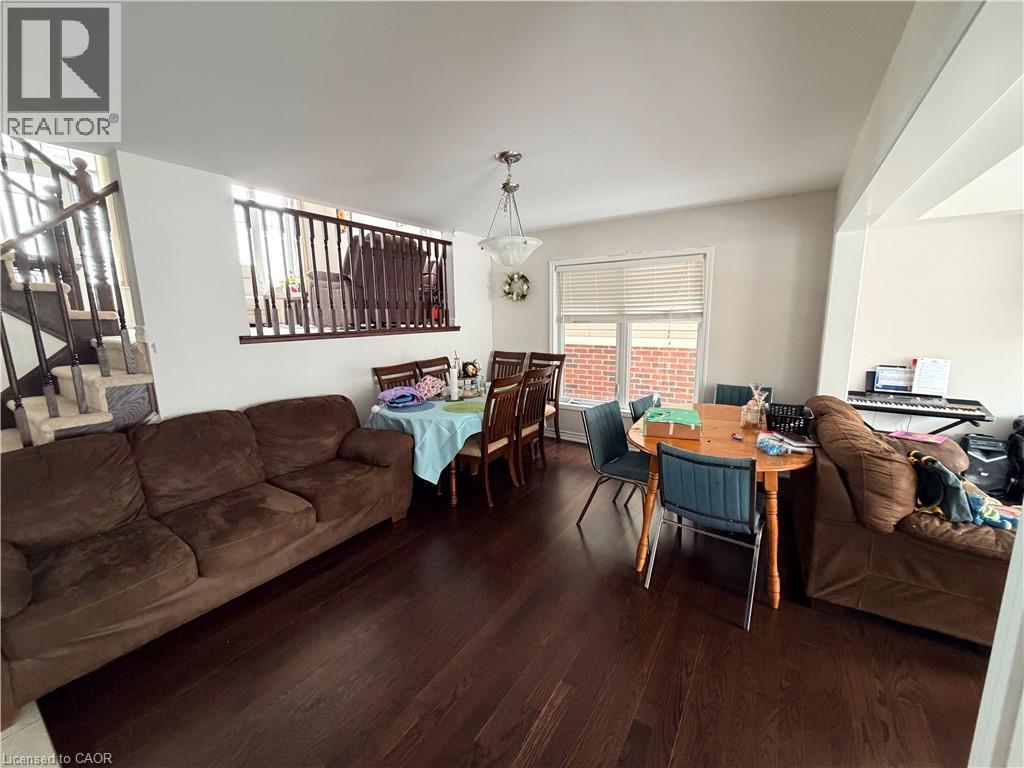 A living room with a brown couch and a dining table with chairs.