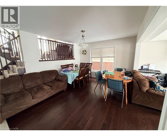 A living room with a brown couch and a dining table with chairs.