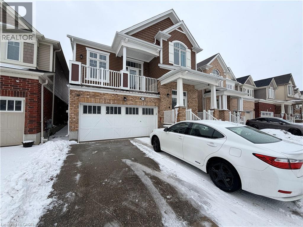 A white car is parked in front of a house with a snow-covered driveway.