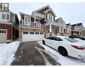 A white car is parked in front of a house with a snow-covered driveway.