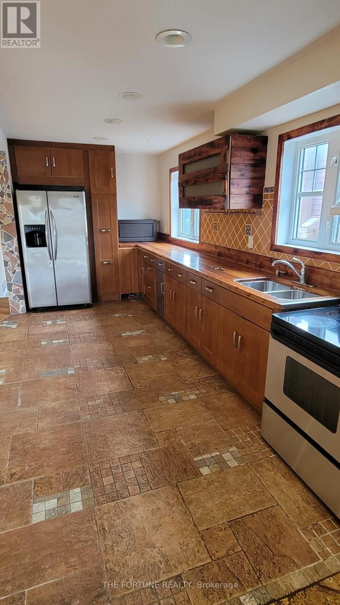 A kitchen with brown tiled floors and wooden cabinets.