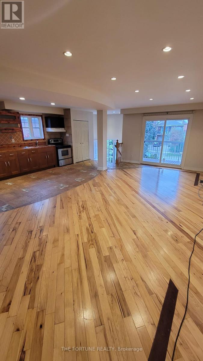 A spacious room with wooden flooring and a large window.