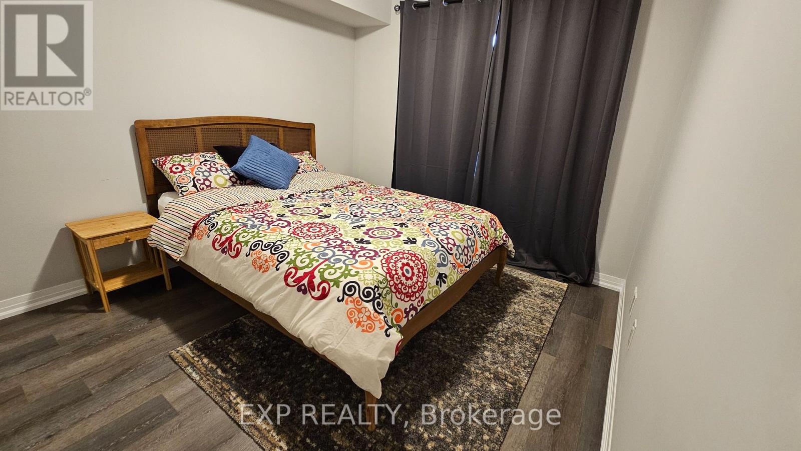 A bedroom with a bed and a small wooden nightstand.