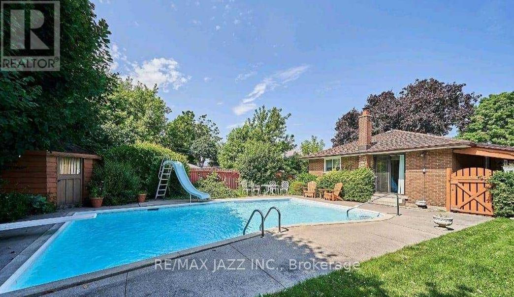 A swimming pool in a backyard with a slide and a house in the background.