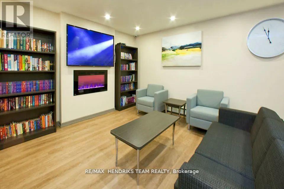 A living room with a grey couch, a coffee table, a bookshelf, and a flat screen TV mounted on the wall.