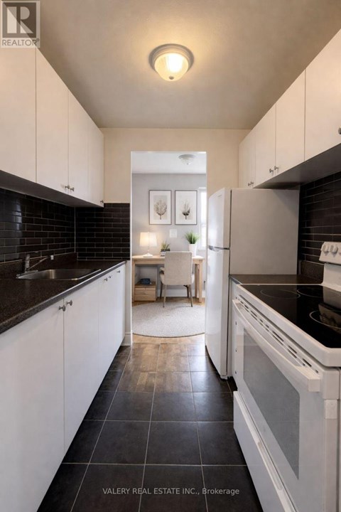 A modern kitchen with white cabinets and black countertops.