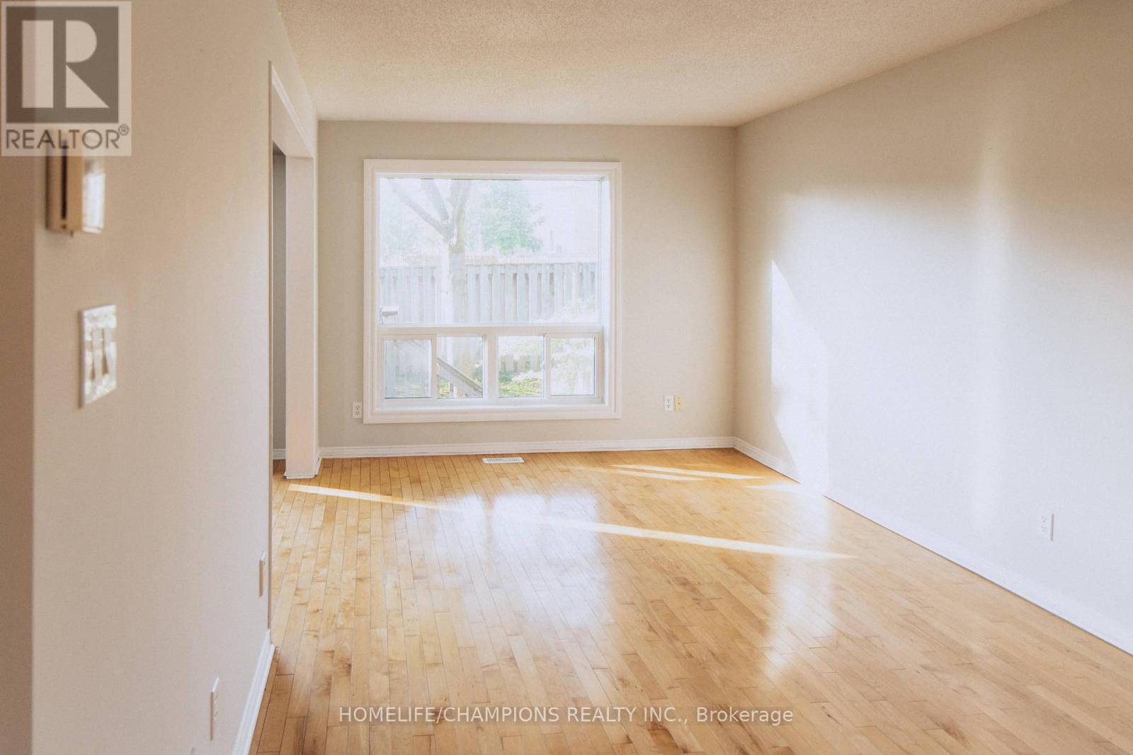 A room with wooden floors and a large window overlooking a deck.