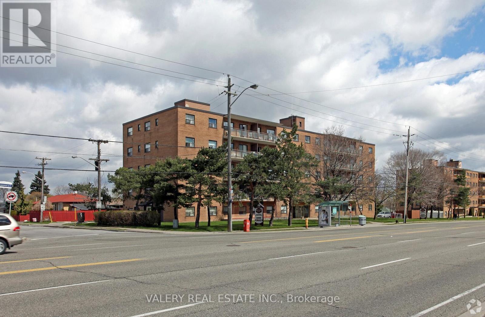 A street view of a residential area with apartment buildings and a car parked on the side of the road.