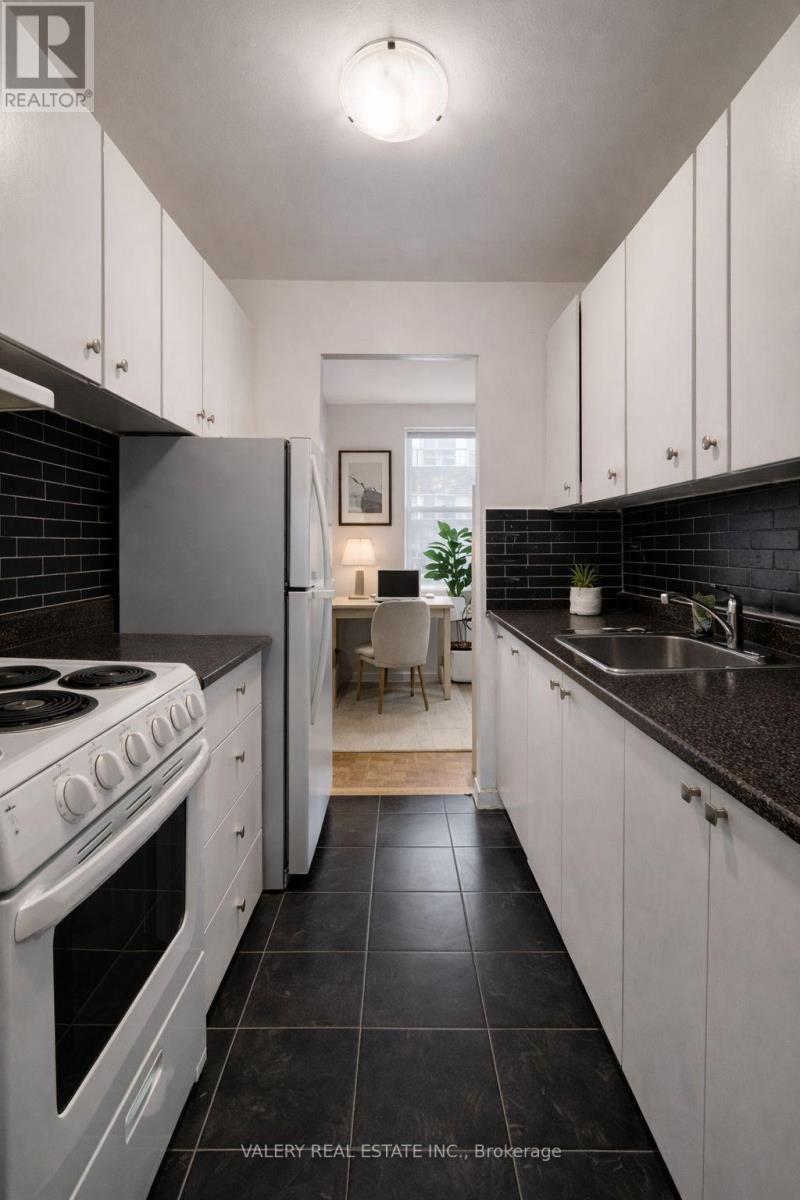 A modern kitchen with white cabinets and black countertops.