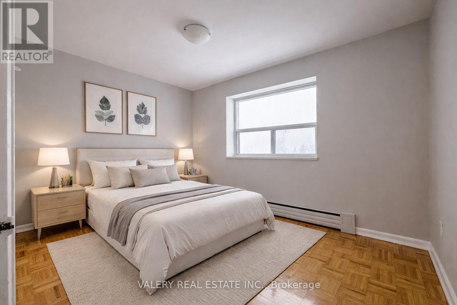 A bedroom with a bed, nightstands, and pictures on the wall.
