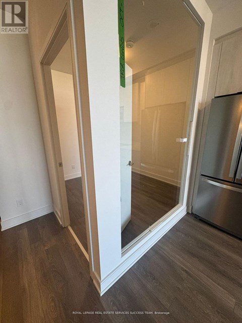 A kitchen with a refrigerator and a mirror on the wall.