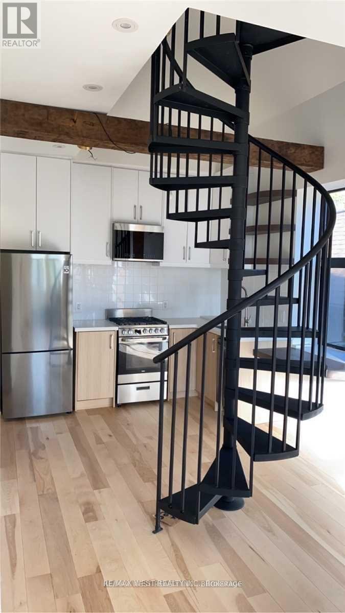 A spiral staircase in a home with a kitchen in the background.
