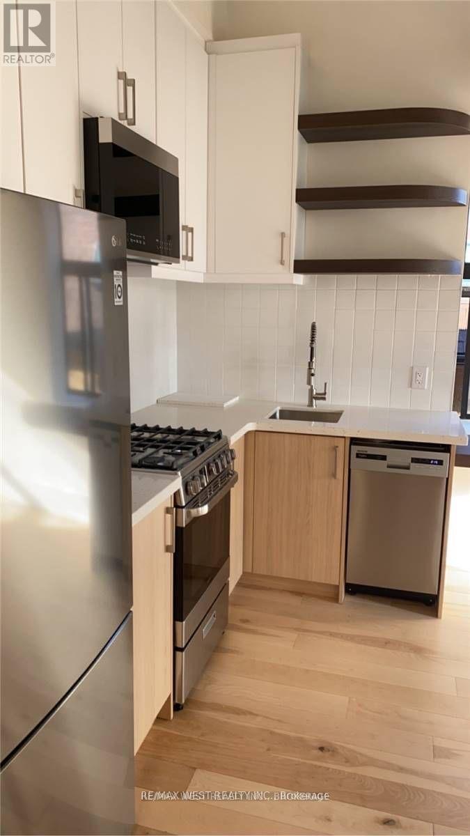 A kitchen with a stainless steel refrigerator and wooden cabinets.