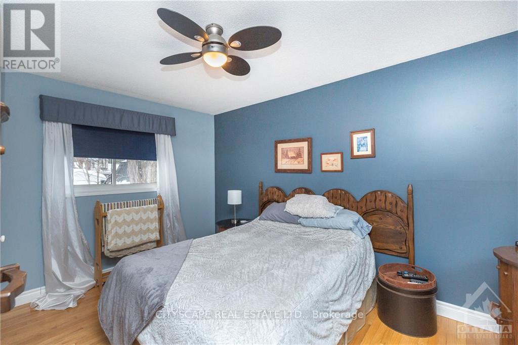 A bedroom with a bed, a fan, and pictures on the wall.