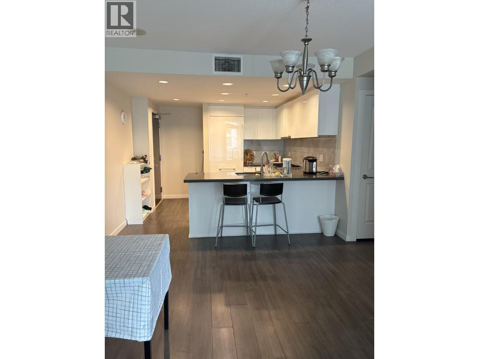 A kitchen with a table and chairs in the foreground and a dining area in the background.