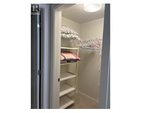 A white closet with a shelf and a pillow on it.