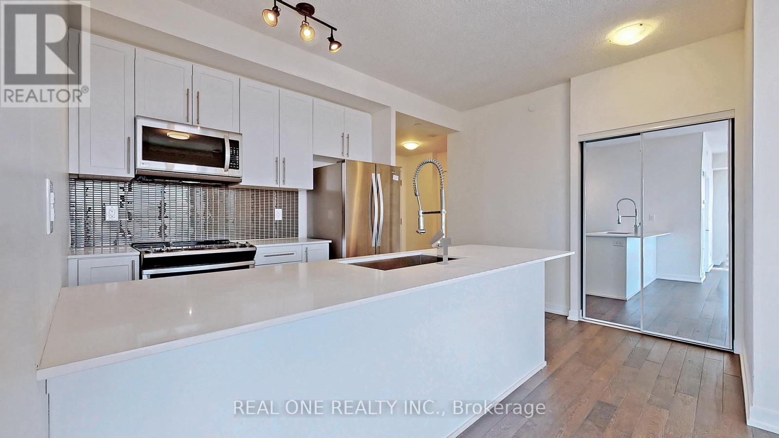 A white kitchen with a microwave above the stove and a refrigerator to the side.