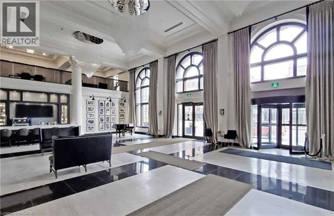 A spacious living room with a black sofa and a chandelier.