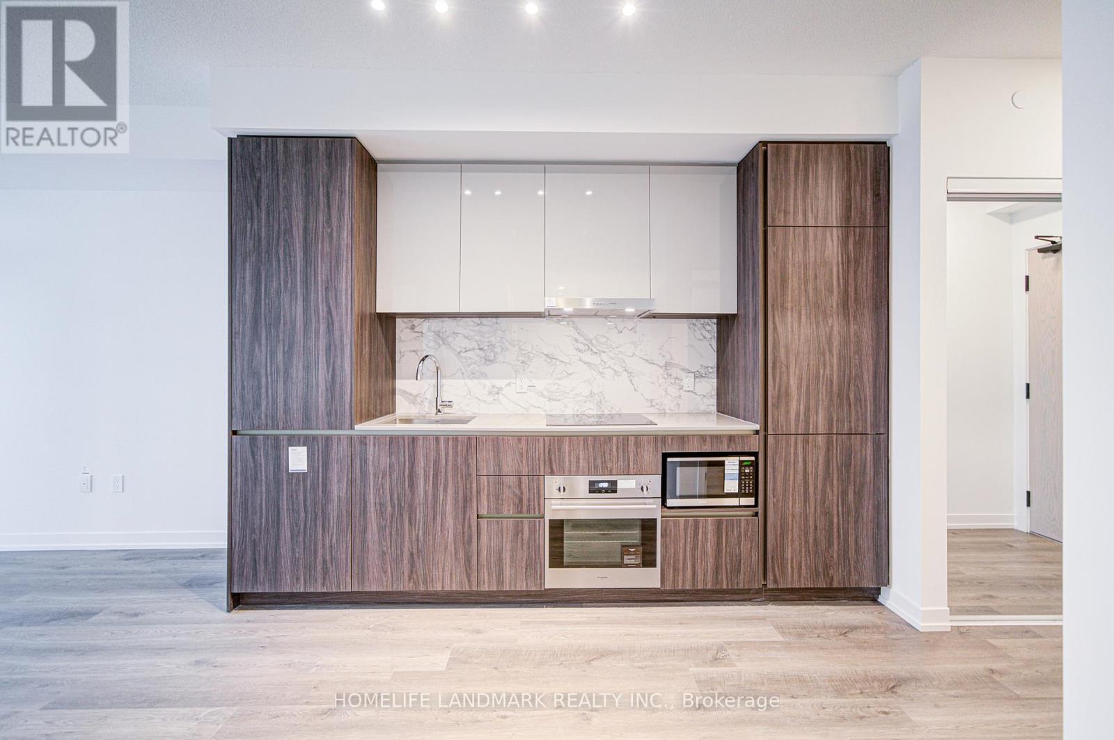 A modern kitchen with a marble countertop and wooden cabinets.