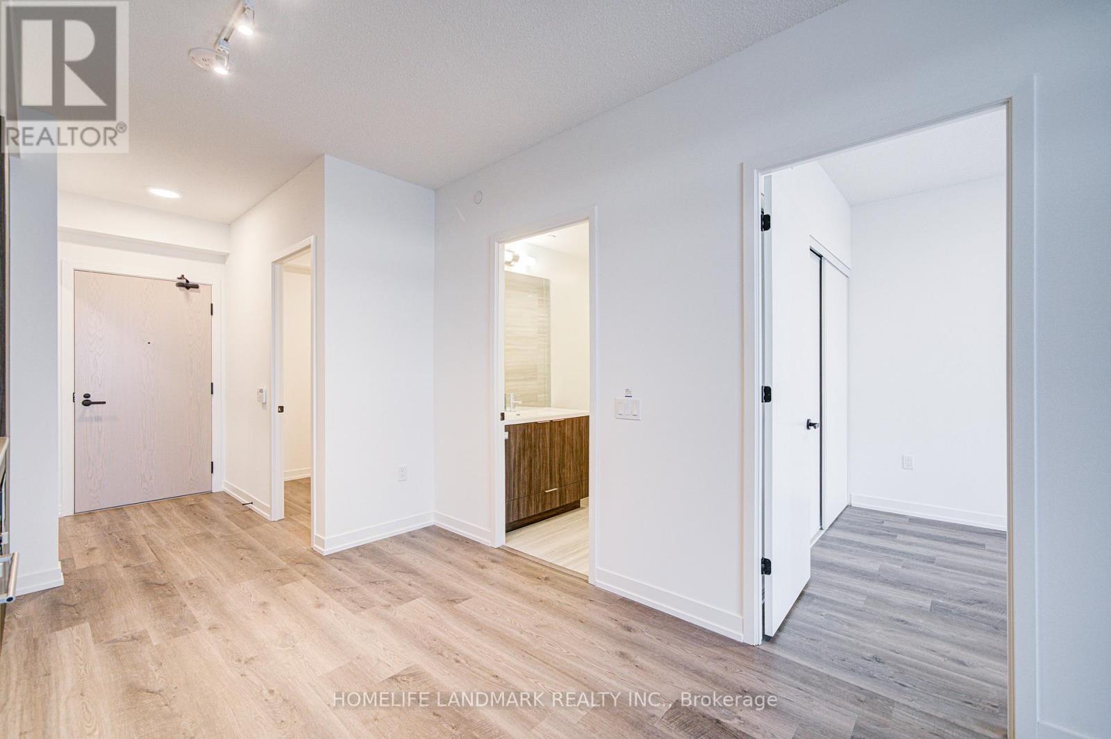 A spacious room with white walls and wooden flooring, with a door on the left and a doorway on the right.